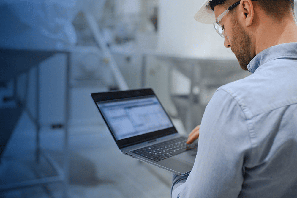 Homme dans une usine avec son ordinateur portable dans les mains