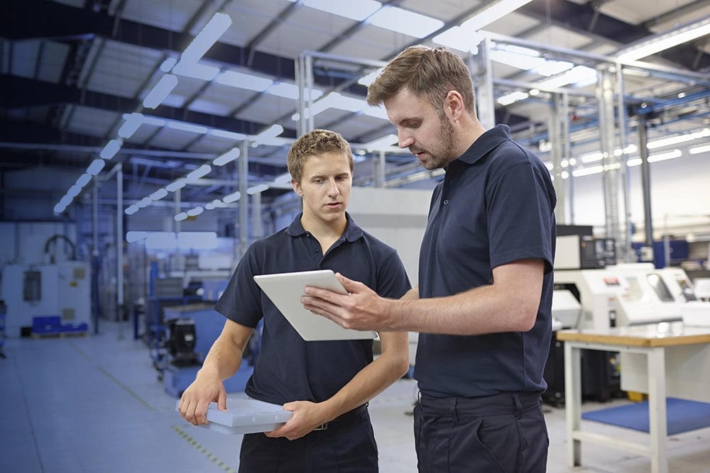 Deux hommes qui collaborent sur une tablette dans une usine