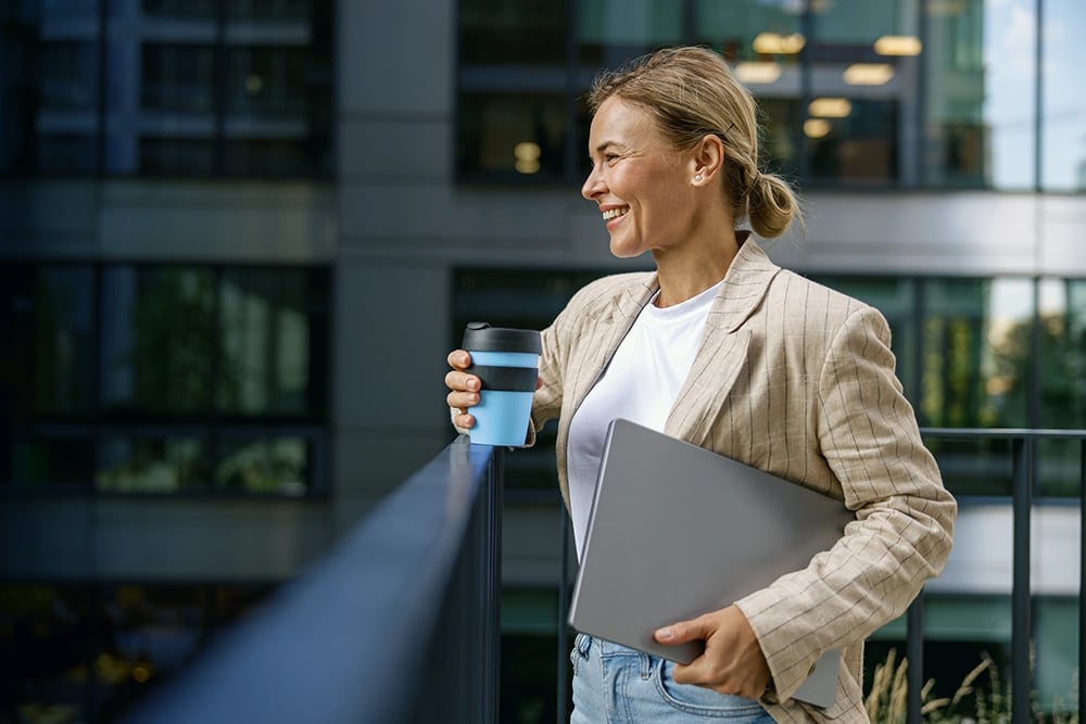 Femme d'affaires souriante tenant son laptop et son café